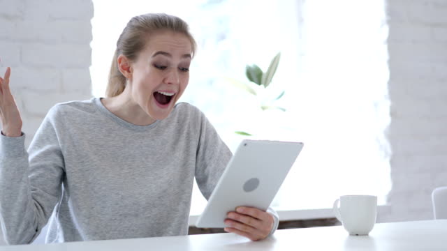 Young-Woman-Celebrating-Success-while-Using-Tablet