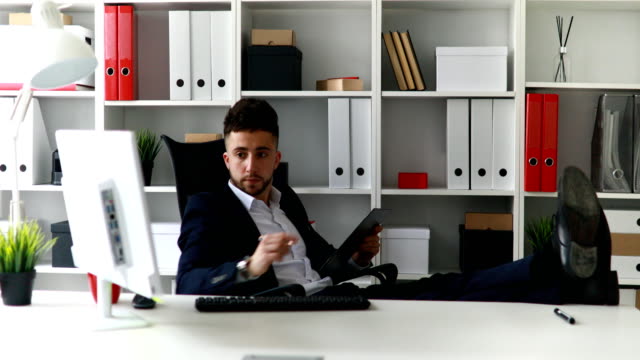 businessman-working-with-legs-on-table-in-office