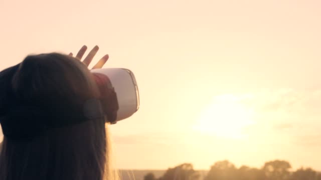 Schöne-Mädchen-in-einem-goldenen-Weizenfeld-nutzt-virtual-Reality-Brille-in-den-Sonnenuntergang-in-Zeitlupe