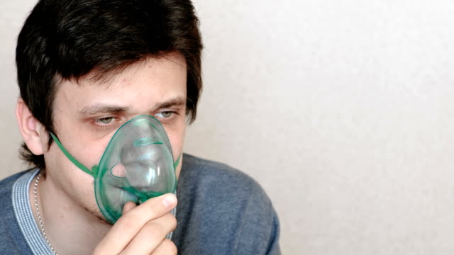 Verwenden-Sie-Vernebler-und-Inhalator-für-die-Behandlung.-Junger-Mann-durch-Inhalator-Maske-Einatmen.-Seitenansicht.