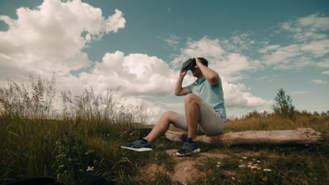 Man-in-Virtual-Reality-Headset-sitting-at-nature.-Male-watching-video-360
