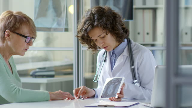 Frau-Doktor-zeigen-Röntgenbild-auf-Tablet,-Senior-Woman