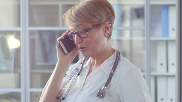 Mediana-edad-Doctor-mujer-hablando-por-teléfono-celular