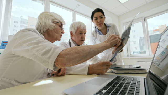 Senior-weiblichen-Praktizierenden-Röntgenbild-mit-Kollegen-diskutieren