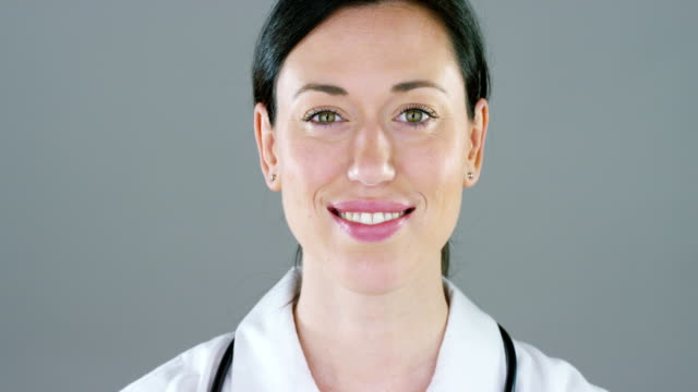 Porträt-von-einer-Ärztin-mit-weißen-Kittel-und-Stethoskop-lächelnd-Blick-in-Kamera-auf-weißem-Hintergrund.