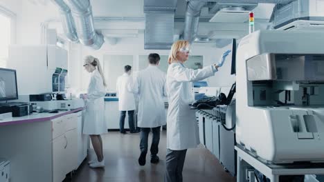 Team-von-Forschern-arbeiten-am-Computer,-mit-medizinischen-Geräten,-Blut-und-genetische-Materialproben-mit-Spezialmaschinen-im-modernen-Labor-analysieren.