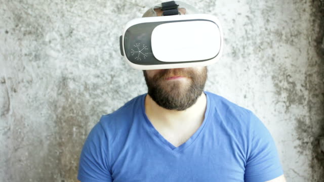 Bärtiger-Mann-verwendet-VR-Kopfhörer-Display-mit-Kopfhörern-für-virtual-Reality-Spiel.