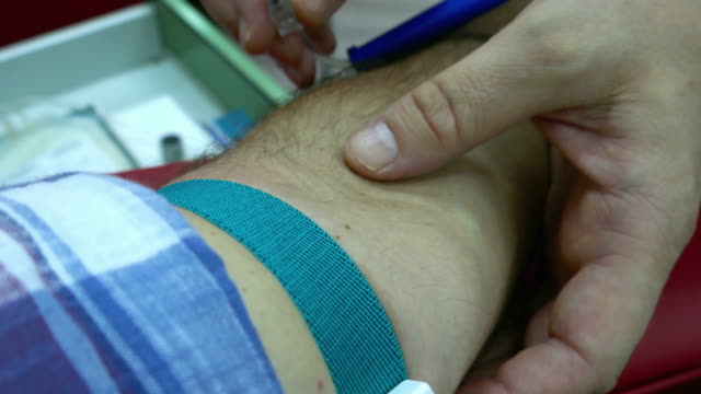 A-nurse-disinfecting-a-persons-arm-and-sticks-the-needle-into-the-vein