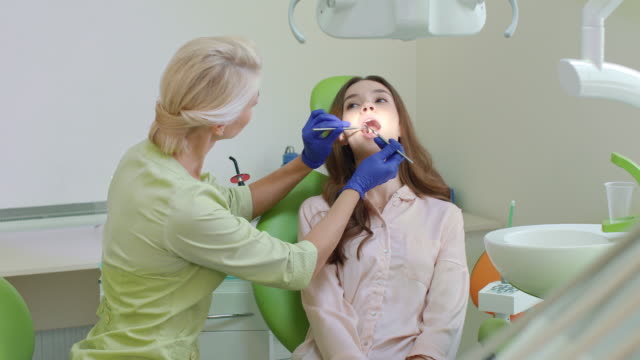 Karies-Behandlung-in-der-Zahnarztpraxis.-Frau-mit-offenem-Mund-im-Zahnarztstuhl