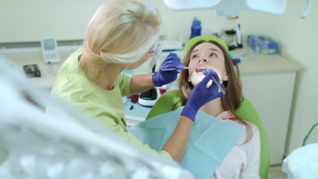 Frau-Zahnarzt-Tampon-aus-Patienten-Mund-herausnehmen.-Zahnschmerzen-Behandlungsprozess