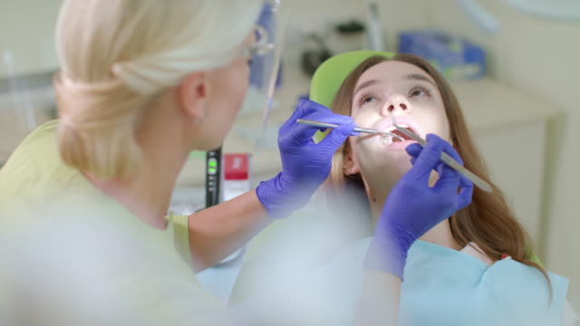 Zähne-Behandlungsprozess-in-Zahnarztpraxis.-Blonde-Zahnarzt-arbeiten-mit-Patienten