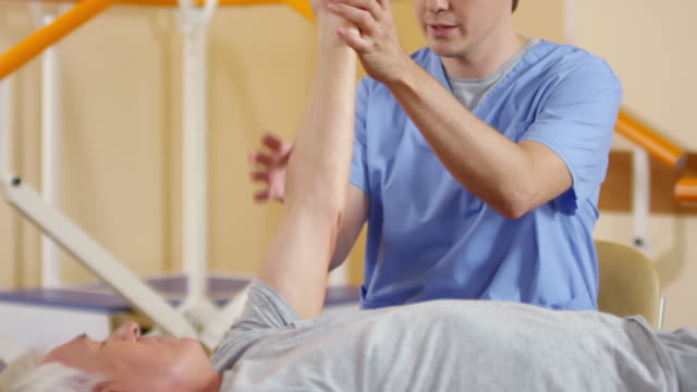 Fisioterapeuta-examinar-la-flexibilidad-del-brazo-del-hombre-alto