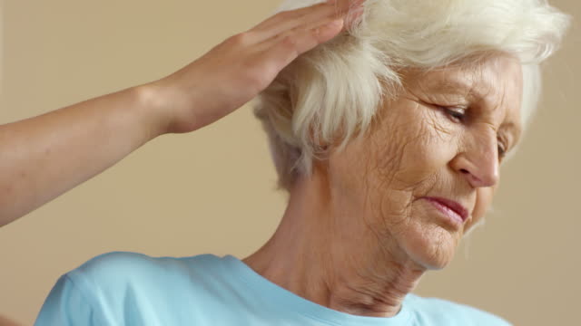 Unrecognizable-Physiotherapist-Tilting-Head-of-Elderly-Patient