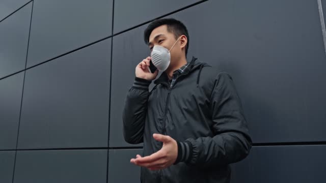 asiatischer-Mann-in-medizinischer-Maske-sprechen-auf-dem-Smartphone