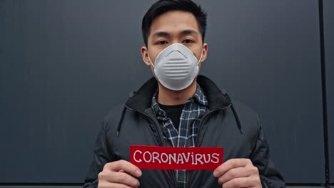 junger-asiatischer-Mann-hält-Papier-mit-Coronavirus-Schriftzug