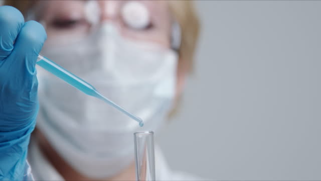 Technician-carefully-drips-the-solution-from-the-pipette-into-glass-tubes.