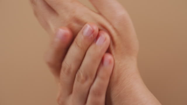 Nahaufnahme-der-Hände-der-Frau,-die-Handdesinfektionsmittel-auf-die-Hände-legen,-um-ihre-Hände-isoliert-über-beige-Hintergrund-zu-waschen.-4K-Video