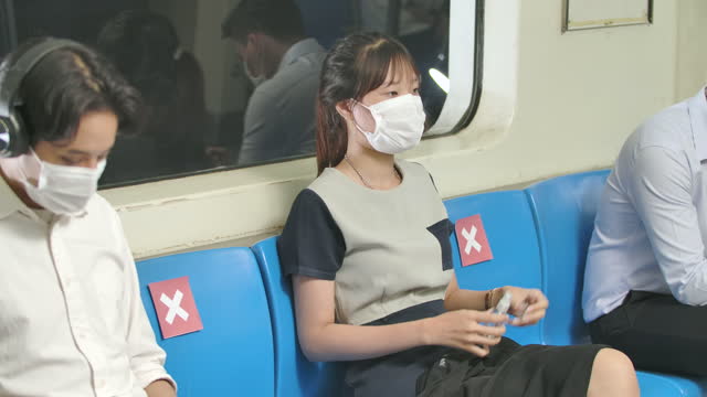 Neue-normale-Lebensstil,-Gruppe-von-asiatischen-Passagier-verschiedene-Berufe-in-der-U-Bahn-Zug-tragen-Maske,-Frau-verwendet-Handdesinfektionsflüssigkeit,-halten-soziale-Entsinnen.-Schutzabschnitt-der-Pandemie-covid-19