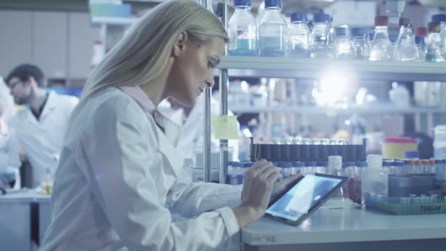 Weibliche-Wissenschaftlerin-benutzt-eine-Tablette,-während-sie-im-Labor-arbeitet.