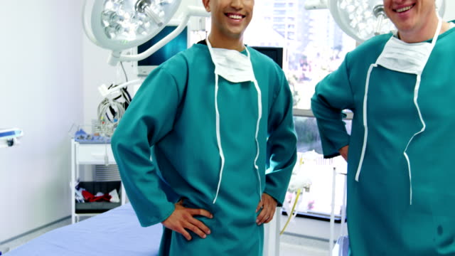 Porträt-von-männlichen-Chirurgen-stehend-mit-Händen-auf-den-Hüften-im-OP-Saal
