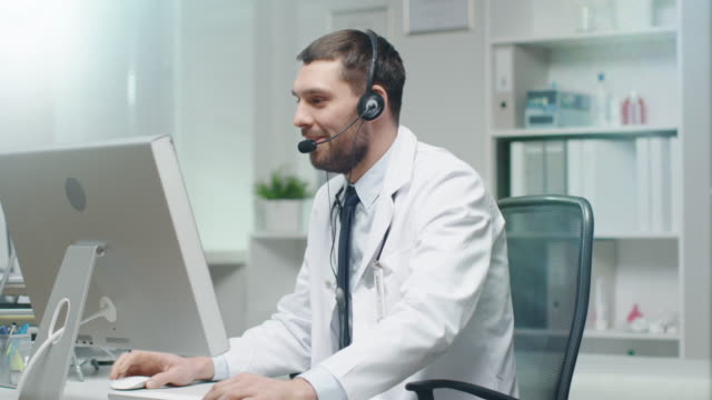 Männlichen-Arzt-berät-Patienten-über-das-Internet.-Er-sitzt-vor-seinem-PC-und-Mikrofon-trägt.