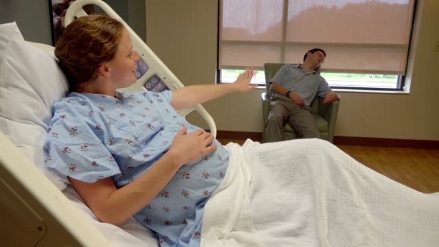 Expecting-Wife-Trying-To-Wake-Up-Sleeping-Husband-In-Hospital