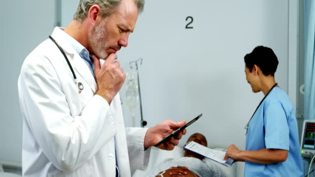 Médico-con-tableta-digital-mientras-la-enfermera-interactúa-con-el-paciente