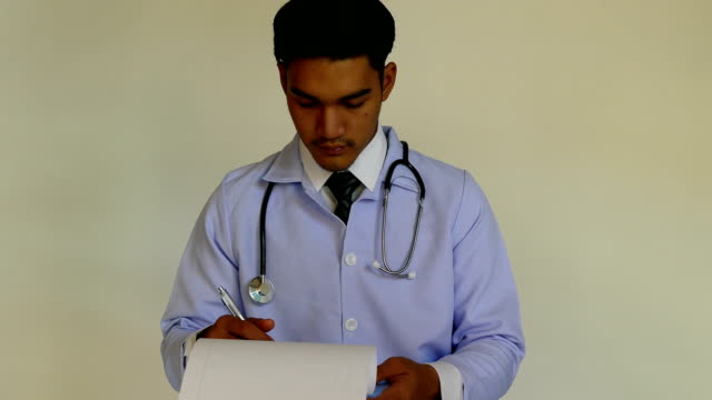 médico-joven-con-un-estetoscopio-alrededor-de-su-cuello-escribiendo-papel-de-prescripción,-llenando-el-registro-del-paciente-en-un-portapapeles