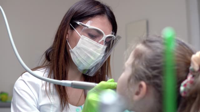 Zahnarzt-reinigt-Mädchens-Zähne-mit-professionellen-Zahnpasta.-Mädchen-mit-weißen-Zähnen-in-der-Zahnarztpraxis.-Schuss-in-4k