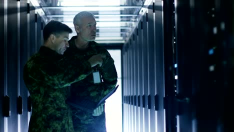 In-Data-Center-Two-Military-Men-Work-with-Open-Server-Rack-Cabinet.-One-Holds-Military-Edition-Laptop.