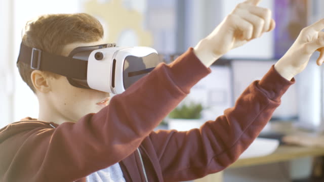 In-einem-Computer-Wissenschaft-Klasse-jungen-tragen-Virtual-Reality-Kopfhörer-arbeitet-an-einem-Programmierung-Projekt.