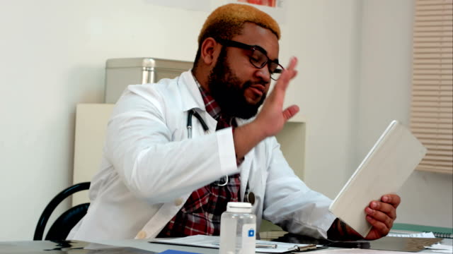 African-american-männlichen-Arzt-erklären-Xray-Ergebnisse-für-Patienten-per-Videoanruf-auf-tablet