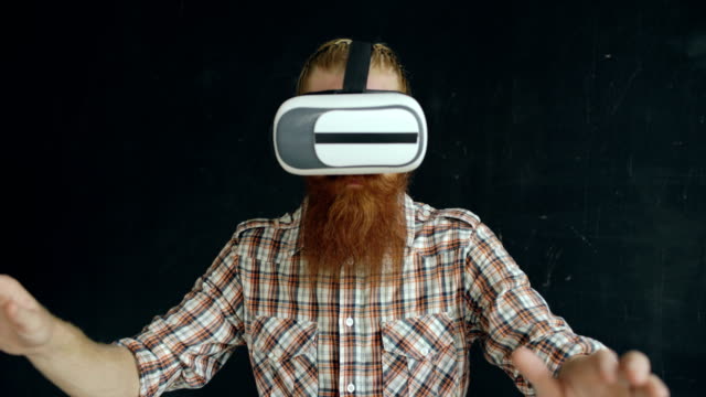 Bärtiger-Mann,-virtual-Reality-Kopfhörer-tragen-und-mit-360-VR-auf-schwarzem-Hintergrund-erleben