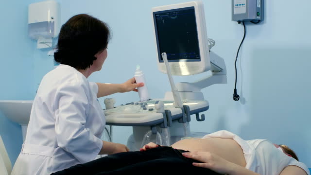 Female-doctor-putting-gel-on-patient-stomach-for-ultrasound-scan