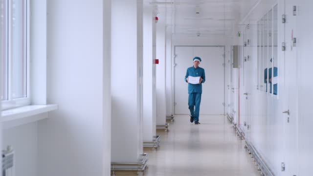 Mann-in-Uniform-tragen-Weißbuch-im-Korridor.-Männliche-Arbeiter-mit-Haufen-von-Papier