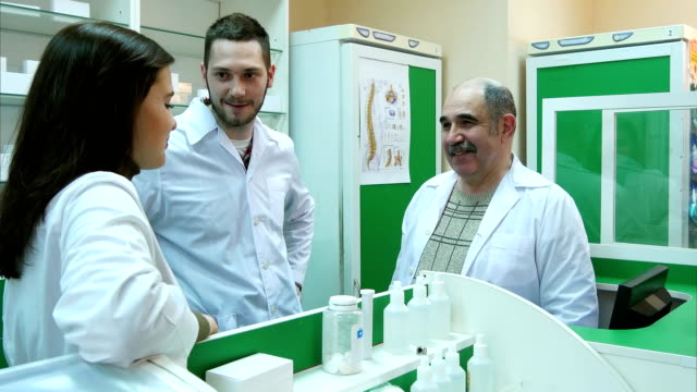 Positive-team-of-pharmacist-talking-and-smiling-at-the-hospital-pharmacy
