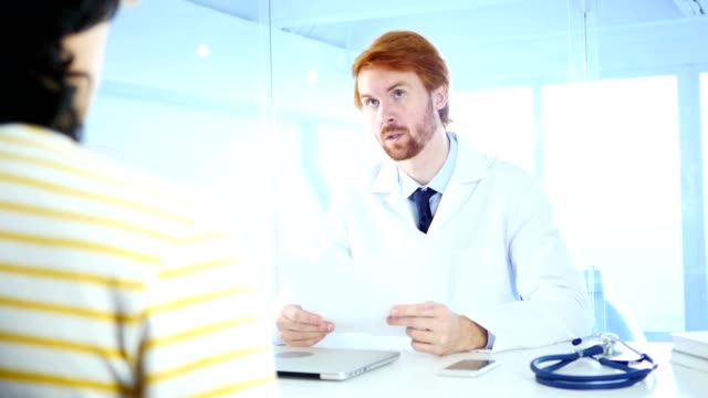Doctor-Reading-Medical-Reports-of-Patient,-Sitting-in-Front