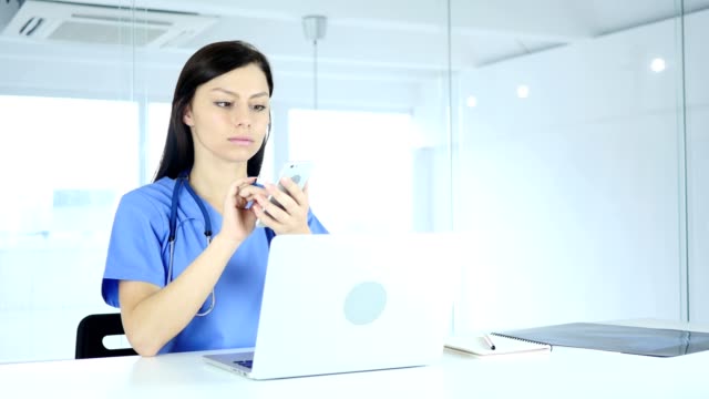 Young-Doctor-Browsing-Online-on-Phone-in-Hospital