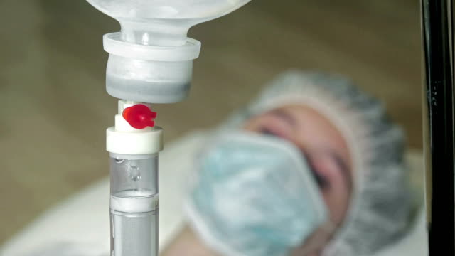 intravenous-saline-drip-with-patient-face-out-of-focus.-UHD-stock-video