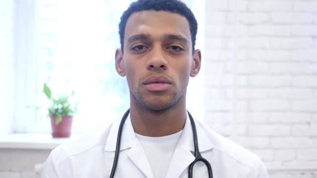 Ernsthafte-African-American-Arzt-Blick-in-die-Kamera-in-Klinik