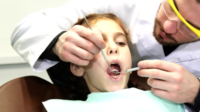 A-serious-doctor-carefully-examines-the-upper-teeth-of-the-young-patient