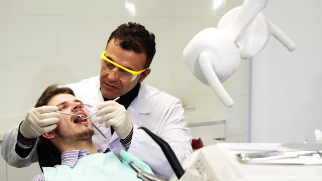 Professionl-mature-male-dentist-performing-dental-examination