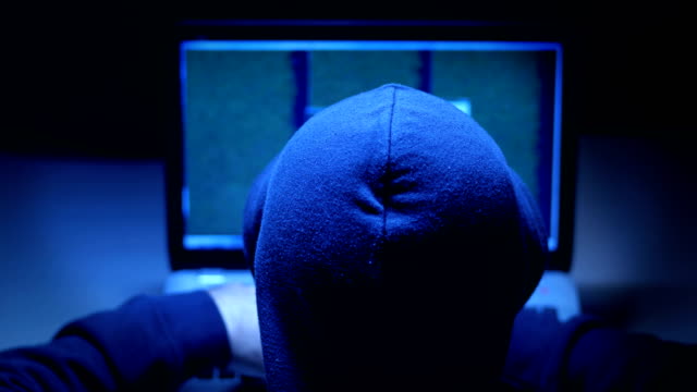 Back-View-Of-A-Hacker-In-Black-Clothes-typing-on-computer-in-the-dark