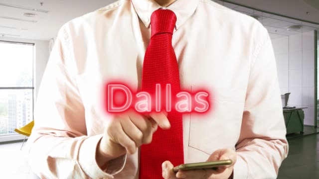Dallas.-Businessman-operating-a-smart-device-chooses-а-city-on-light-background.-Concept:-business-trip,hologram,-technology,-augmented-reality,-future,-travel