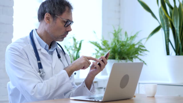 Arzt-surfen-Internet-auf-Smartphone-in-Klinik