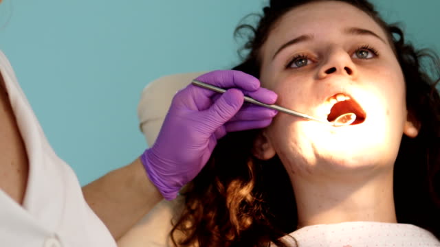 Chequeo-de-los-dientes-en-el-consultorio-del-dentista.-Dentista-examinar-los-dientes-de-las-niñas-en-la-silla-de-dentistas