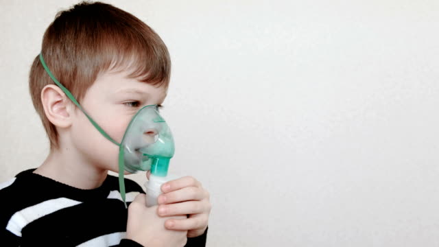Verwenden-Sie-Vernebler-und-Inhalator-für-die-Behandlung.-Junge-durch-Inhalator-Maske-Einatmen.-Seitenansicht.