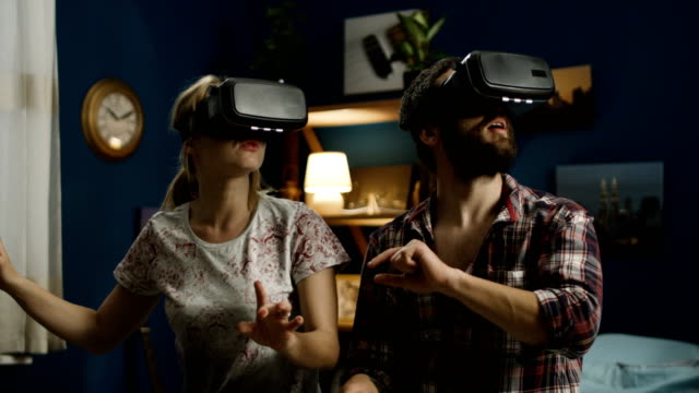 Couple-in-VR-glasses-having-fun-on-bed