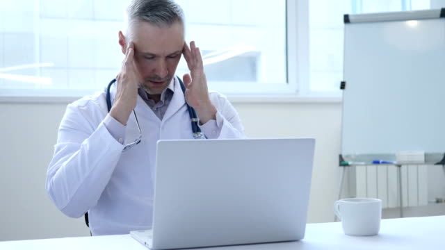 Kopfschmerzen,-müde-Arzt-arbeitet-auf-Laptop