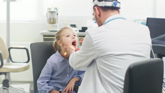Friendly-Doctor-Checks-up-Little-Girl's-Sore-Throat,-Curing-Flu.-Modern-Medical-Health-Care,-Friendly-Pediatrician-and-Bright-Office.